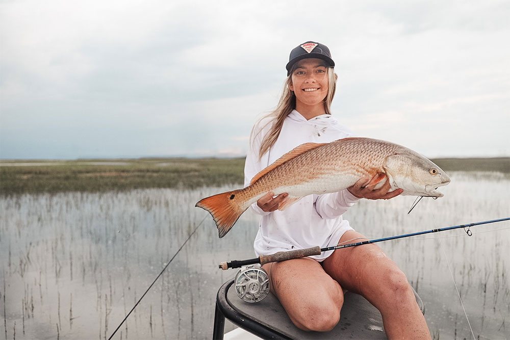 Image of a woman holding a fish, featuring Saltwater Fishing Charters and highlighting their charter rates, capturing the success of their fishing excursions.