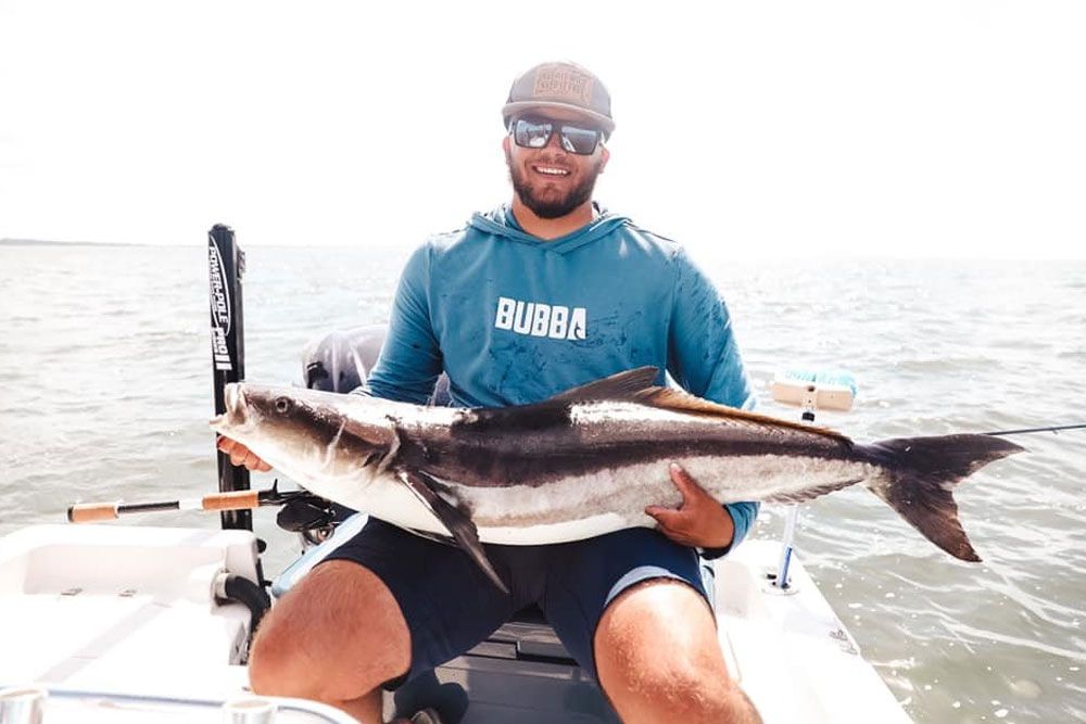 Image of a man holding a fish, featuring Saltwater Fishing Charters and highlighting their charter rates, illustrating the excitement of their fishing trips.