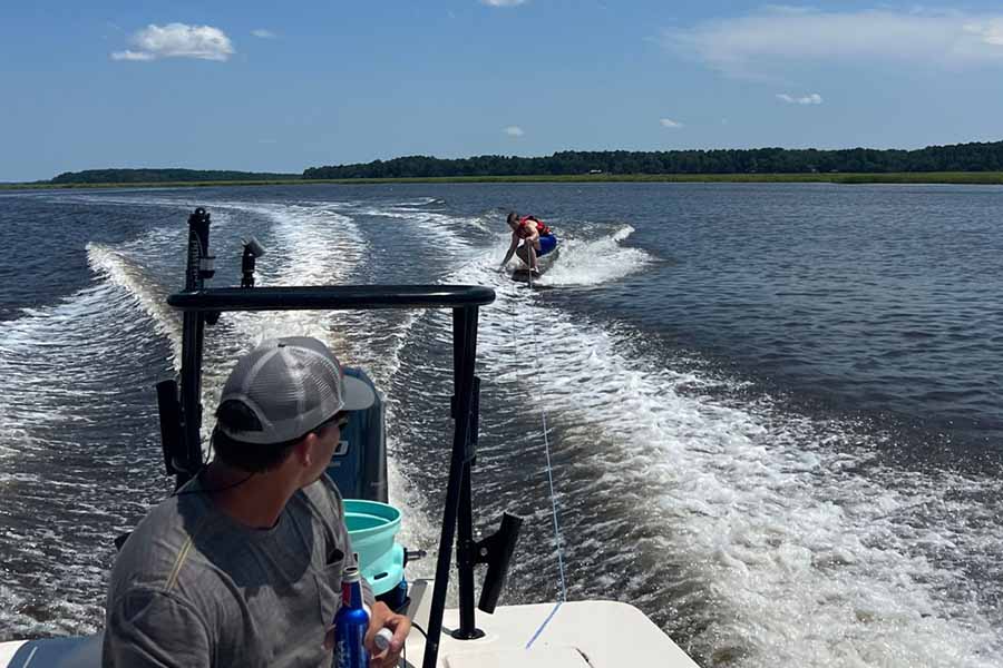 A man surfing the waves during a Saltwater Fishing Charters trip, capturing the adventurous spirit of the experience. The image highlights the additional recreational activities available and aligns with the website's focus on providing information about cruise rates and services.