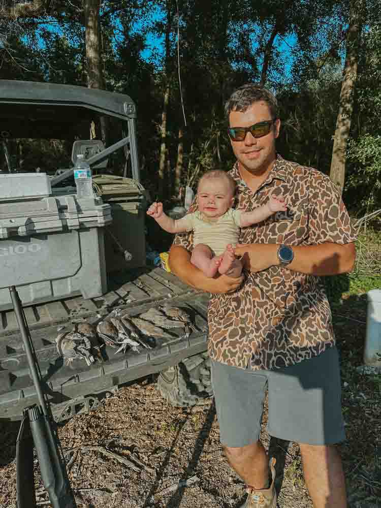 A man smiles while holding a baby during a Saltwater Fishing Charters trip, capturing a special moment. The image emphasizes the family-friendly atmosphere of Saltwater Fishing Charters, aligning with the website's focus on providing memorable fishing adventures and detailed service information.