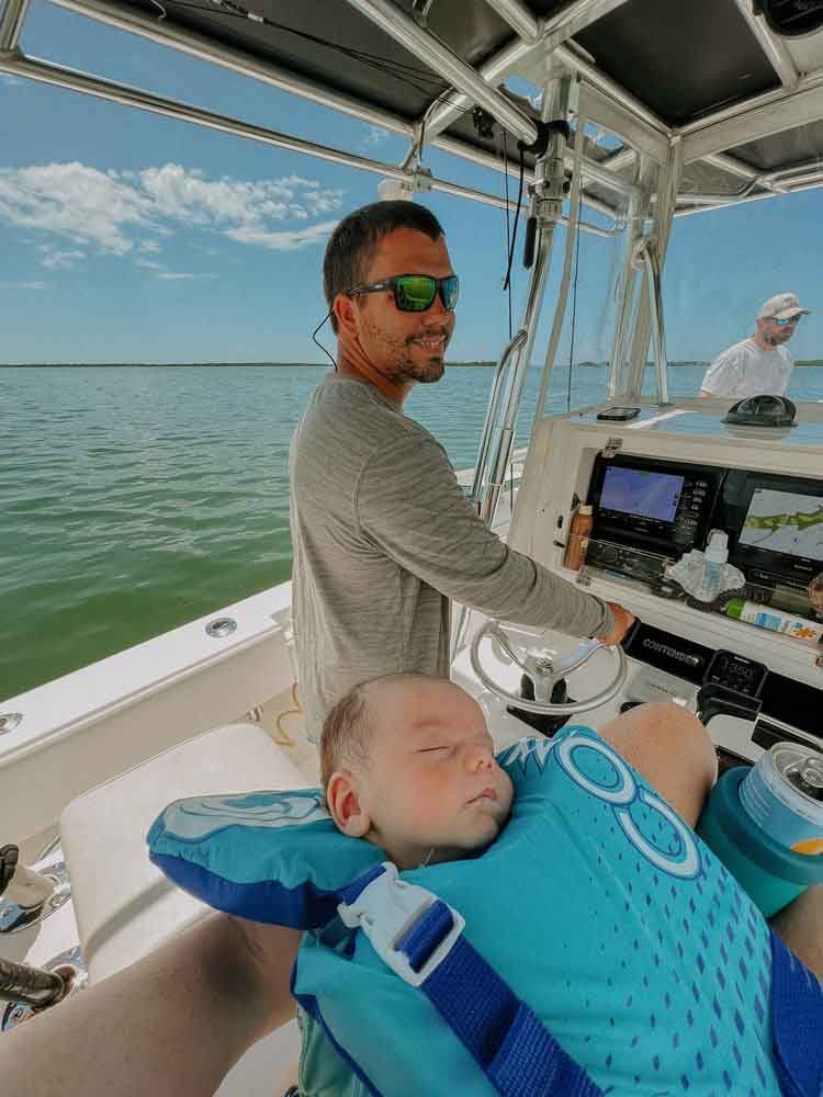 A man smiles with a baby during a Saltwater Fishing Charters trip, capturing a special moment. The image emphasizes the family-friendly atmosphere of Saltwater Fishing Charters, aligning with the website's focus on providing memorable fishing adventures and detailed service information.