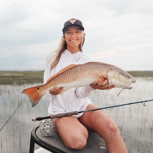 Image of a woman holding a fish, featuring Saltwater Fishing Charters and highlighting their charter rates, capturing the success of their fishing excursions.